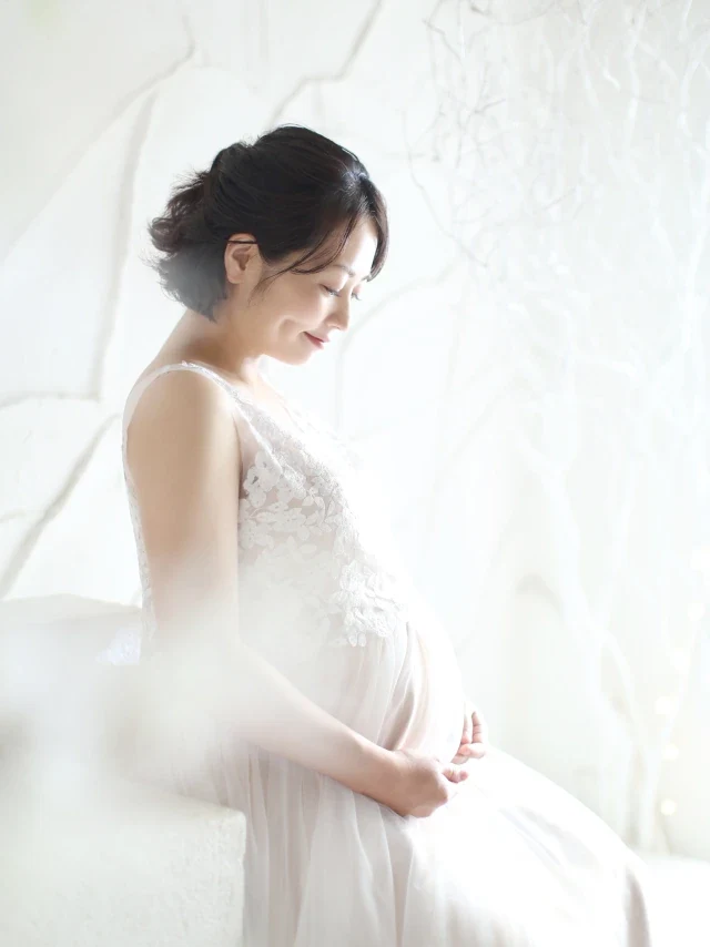 ウェディングドレス姿でおなかに手を添えるマタニティの女性