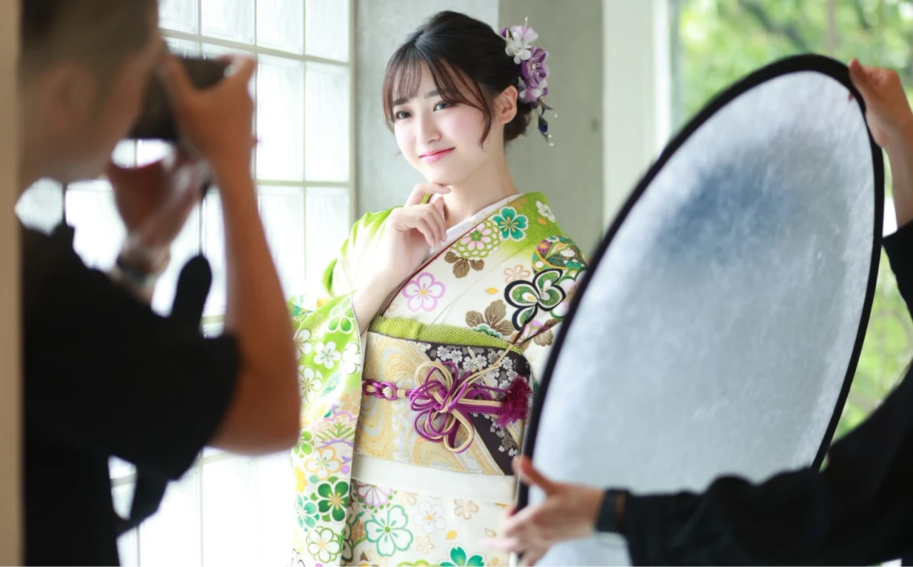 レフ板を使いながら振袖姿の女性を撮影する様子